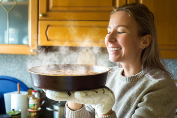 Young woman holding a baking tray with a ready cake