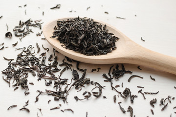 dry black tea in wooden spoon