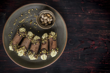 Traditional Italian dessert cannoli with pistachios on wooden background with blank space,selective focus
