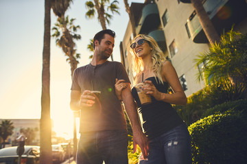 trendy attractive couple walking together with coffee in los angeles