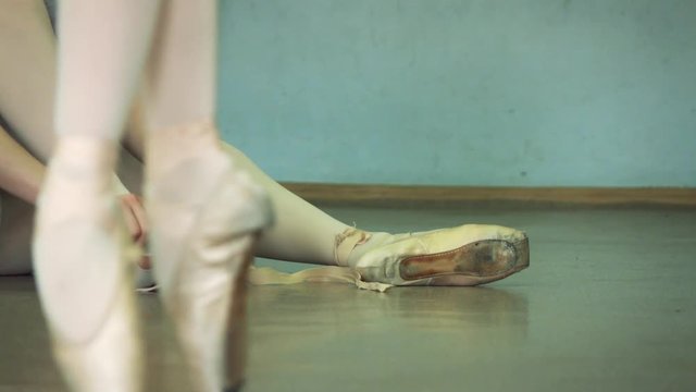 Slow motion footage. Ballerina wears ballet shoes on the background. Dansing foreground