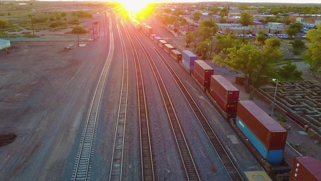 High aerial over a freight train full of containers for export heading into the sunset.