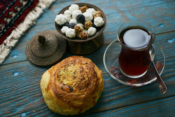 Novruz holiday with Azerbaijan national pastry Gogal and glass of black tea with traditional snack in silver bowl on wooden table background. Delicious dessert holiday food