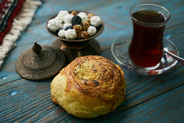 Novruz holiday with Azerbaijan national pastry Gogal and glass of black tea with traditional snack in silver bowl on wooden table background. Delicious dessert holiday food