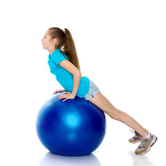 little girl doing exercises on a big ball for fitness.