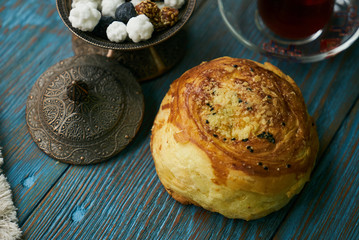 Novruz holiday with Azerbaijan national pastry Gogal and glass of black tea with traditional snack in silver bowl on wooden table background. Delicious dessert holiday food