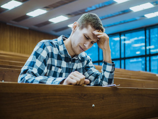 Fototapeta premium young student sitting in the lecture hall on seminar writting down in notebook