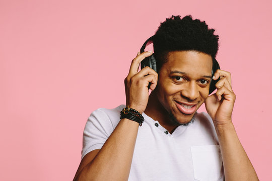 Portrait of a smiling guy listening to music holding headphones