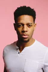 Obraz premium Close up of a cool African American guy in white shirt on pink background