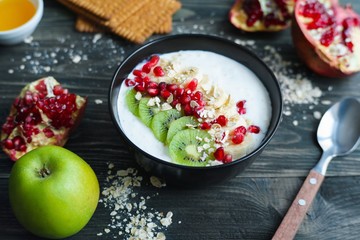 Healthy and tasty low calorie energizing breakfast. Oatmeal and yoghurt smoothie bowl with kiwi slices and pomegranate, delicious diet food