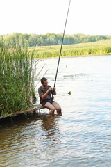 A young man is fishing on the beautiful river bank