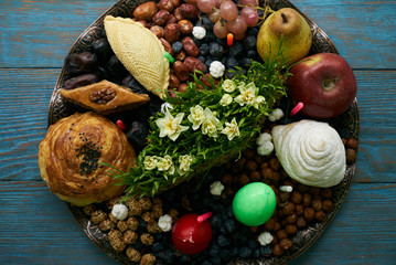 Novruz tray with Azerbaijan national pastry pakhlava,  shekerbura, gogal, badambura and dry snacks with green semeni wheat grass on rustic wooden table background