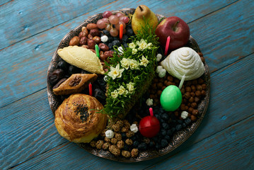 Novruz tray with Azerbaijan national pastry pakhlava,  shekerbura, gogal, badambura and dry snacks with green semeni wheat grass on rustic wooden table background