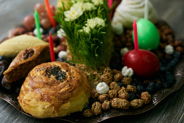 Novruz tray with Azerbaijan national pastry pakhlava,  shekerbura, gogal, badambura and dry snacks with green semeni wheat grass on rustic wooden table background