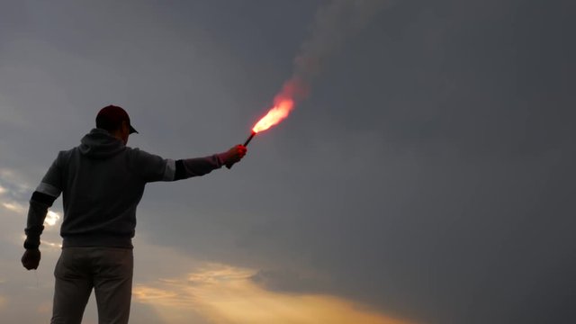 Football fan with hand flare on the clouds background