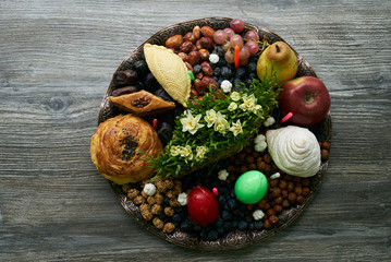 Novruz tray with Azerbaijan national pastry pakhlava,  shekerbura, gogal, badambura and dry snacks with green semeni wheat grass on rustic wooden table background