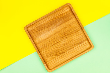 Squares wooden plate on split colorful background yellow / blue