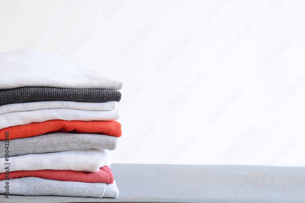 Wall mural Stack of colorful folded shirts on gray table