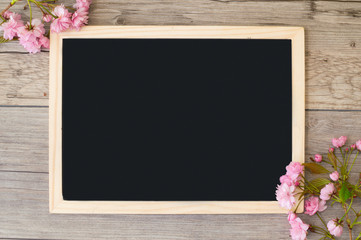 Branches of pink flowering sakura at the corners of the board. Copy space on blackboard