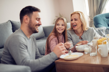 Family of three having breakfast in the morning together in their living room