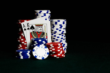 Stacks of poker chips on a gambling table with an ace and king representing a Blackjack win playing the game 21