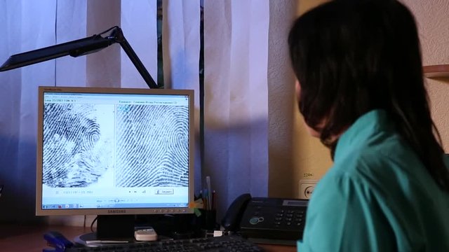 Woman expert look at fingerprint on computer screen