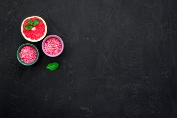Obraz na płótnie Canvas Natural citrus cosmetics with grapefruit salt on black background top view space for text