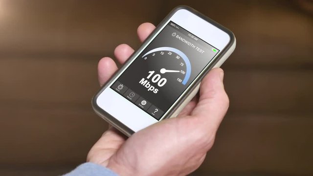 A man tests his home Internet bandwidth by running a speed test app on his smartphone. Result is 100 Mbps.  	