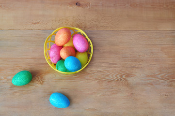 Colorful Easter eggs in basket on wooden background