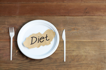 Empty white plate with the inscription diet near knife and fork. The concept of the diet.