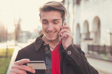 Smiling man with card talking on phone