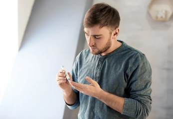 Diabetic man taking blood sample with lancet pen at home