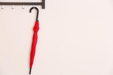 Stylish red umbrella hanging on wall indoors