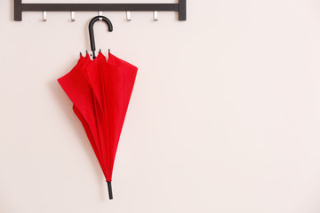 Stylish red umbrella hanging on wall indoors © Africa Studio