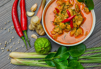 Chicken panang curry in the white bowl and fresh spice on brown wooden background Thai food