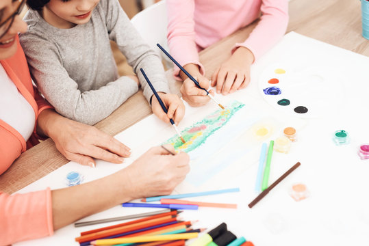 Beautiful elderly woman teaches children to draw. Little children draw. Drawing lessons.