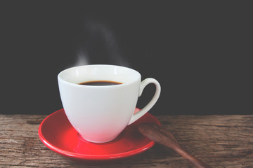 Cup of coffee on rustic wooden table on black background, Vintage and retro filter effect