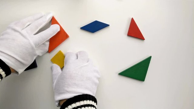 man playing wooden tangram and shaping it like a flying butterfly on white