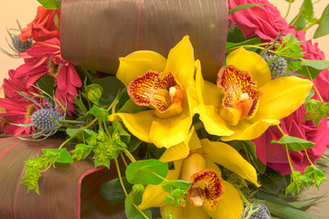 Pink roses, yellow cymbidium , green mums, and palms in a tropical bouquet