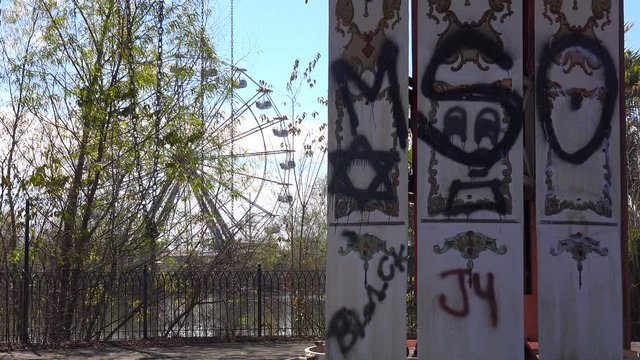 An abandoned and graffiti covered ferris wheel at an amusement park presents a spooky and haunted image.