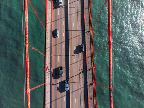 Cars moving on the asphalt road lanes on brige above the water. View from the top.