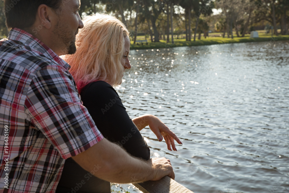 Wall mural happy couple watches setting sun on the lake