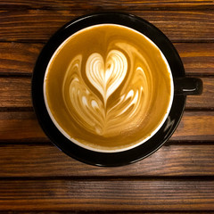 Heart shaped foam design on a single mocha in a mug on a wood slat table