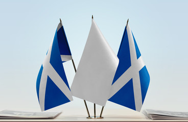 Two flags of Scotland with a white flag in the middle