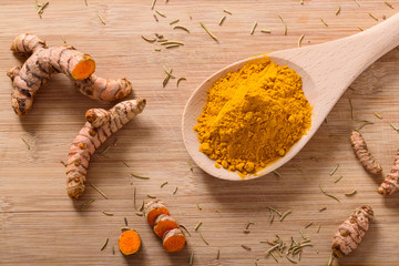 Above view of Turmeric roots and turmeric powder on a wooden surface