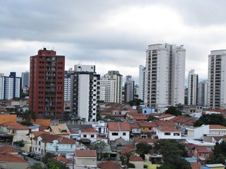 Naklejka premium Vista urbana de São Paulo/SP em dia nublado, com casas no primeiro plano e arranha-céus ao fundo, mostrando o contraste entre a arquitetura residencial e os prédios modernos da metrópole