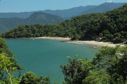 Vista panor&acirc;mica das praias da Almada e do Engenho em Ubatuba/SP, com mar tranquilo, montanhas cobertas de vegeta&ccedil;&atilde;o e c&eacute;u ensolarado, destacando a beleza natural do litoral norte paulista