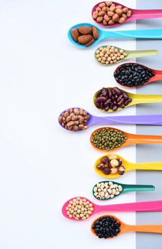 Assortment of beans and lentils in wooden spoon on teak wood background