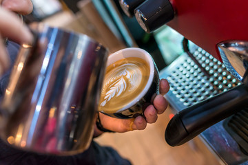 Coffee maker with latte art in shop by barista