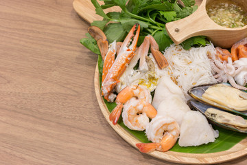 Blanched seafood and spicy sauce in wooden dish on table with a copy space